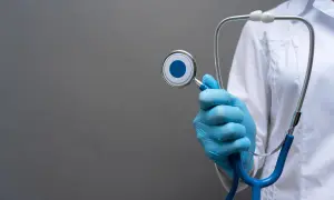 Mano con guanto blu tiene uno stetoscopio, simbolo del piano di studi medicina San Raffaele.