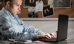 Giovane donna analizza prove su un laptop, un'indagine di criminologia a Milano.