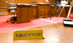 Targhetta "Pubblico Ministero" su un tavolo in un'aula di tribunale. Chi è il pubblico ministero? È colui che rappresenta l'accusa.