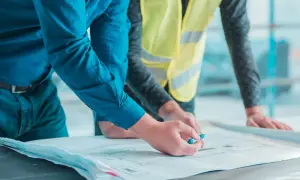 Un geometra di cantiere esamina un progetto con un collega.