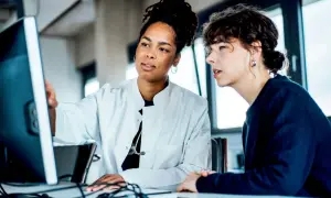 Due medici discutono al computer, forse analizzando dati su quanto guadagna un medico di base.