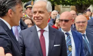 Uomini in abito scuro e cravatta, uno sorride. Dietro, un uomo con cappello da ufficiale. Forse un evento che illustra come si diventa prefetto.
