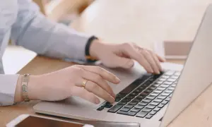 Mani che digitano su un laptop, cercando "università mercatorum recensioni" per valutare la formazione.