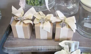 Piccoli pacchetti regalo marroni con fiocchi beige e ciondoli ad albero, perfetti per chi ama lavorare da casa confezionando oggetti.
