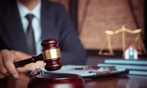 Giudice con martelletto, bilancia della giustizia e casa in miniatura. Un futuro master criminologia pegaso potrebbe studiare questo caso.