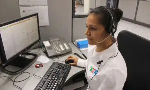 Operatrice al centro di controllo, forse per offerte lavoro cup strutture sanitarie, con cuffie e microfono, davanti a un computer con mappa.