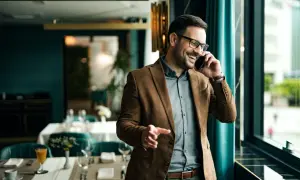 Un uomo sorride al telefono, un esempio di come un **innovation manager cosa fa**: gestisce idee e progetti con entusiasmo, in un ambiente moderno.