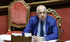 Uomo con completo blu e cravatta, seduto in un'aula istituzionale. Un esempio di chi ha deciso di diventare magistrato a 50 anni, con determinazione.
