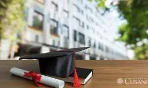 Cappello da laureato, pergamena e libro su un tavolo di legno. Unicusano riconosciuta dal MIUR, simbolo di successo accademico.