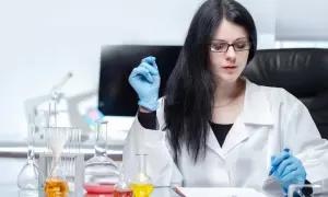 Ingegnere biomedico al lavoro in laboratorio, con provette e becher pieni di liquidi colorati.