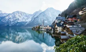 Villaggio alpino con case in legno sul lago, montagne innevate sullo sfondo. Ideale per offerte di lavoro stagione invernale vitto e alloggio.