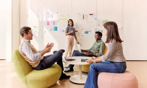 Team discute idee davanti a lavagna con grafici. Eni assume 50 diplomati e laureati, offrendo opportunità di crescita.