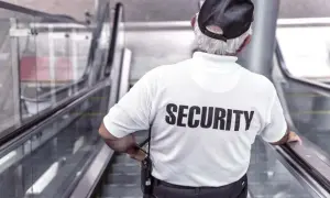 Un buttafuori con la scritta "SECURITY" sulla schiena, su una scala mobile. Chissà quanto guadagna un buttafuori per questo lavoro.