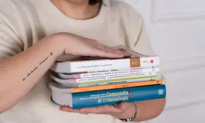 Mani che sorreggono libri, tra cui un "Compendio di criminologia". Quanti anni sono passati da quando si è iniziato a studiare il crimine?