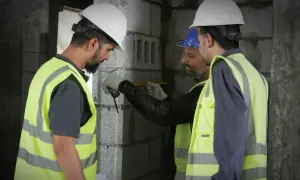 Ingegneri civili al lavoro, misurano con precisione una parete in costruzione.