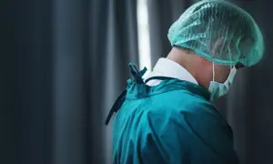Professionista sanitario in camice verde e cuffia, con mascherina. Cerca offerte lavoro OSS per un futuro nel settore.