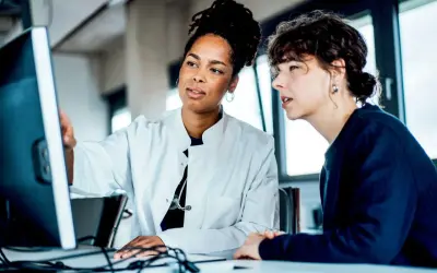 Due medici discutono al computer, forse analizzando dati su quanto guadagna un medico di base.