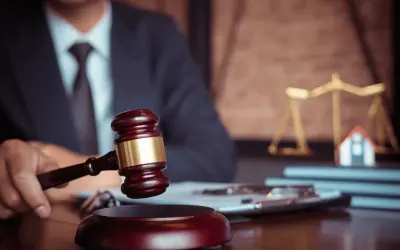 Giudice con martelletto, bilancia della giustizia e casa in miniatura. Un futuro master criminologia pegaso potrebbe studiare questo caso.
