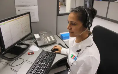 Operatrice al centro di controllo, forse per offerte lavoro cup strutture sanitarie, con cuffie e microfono, davanti a un computer con mappa.