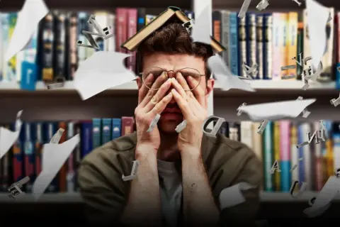 Studente sopraffatto tra libri e lettere volanti, riflette le sfide dell'università e degli sbocchi lavorativi.