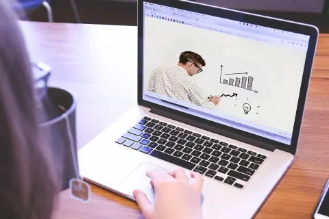 Uomo disegna grafico su schermo laptop, mostrando come le fabbriche che danno lavoro a casa possono far crescere un'idea.