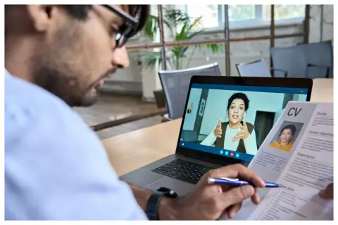 Uomo in videochiamata per un colloquio di lavoro da casa, con il suo CV aperto.