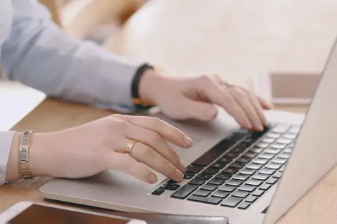 Mani che digitano su un laptop, cercando "università mercatorum recensioni" per valutare la formazione.