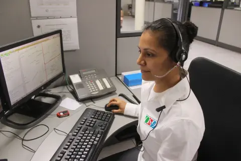 Operatrice al centro di controllo, forse per offerte lavoro cup strutture sanitarie, con cuffie e microfono, davanti a un computer con mappa.