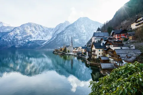 Villaggio alpino con case in legno sul lago, montagne innevate sullo sfondo. Ideale per offerte di lavoro stagione invernale vitto e alloggio.