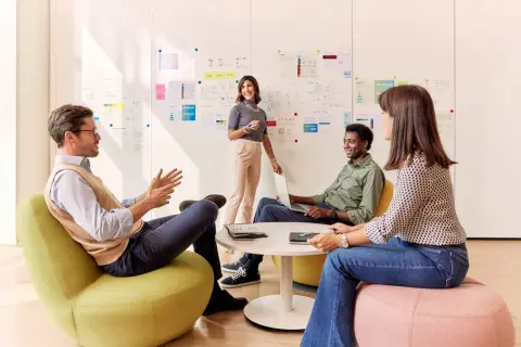 Team discute idee davanti a lavagna con grafici. Eni assume 50 diplomati e laureati, offrendo opportunità di crescita.