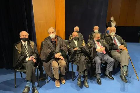 Uomini in toga seduti, alcuni con mascherina. Un uomo anziano potrebbe diventare avvocato a 50 anni, dimostrando che non è mai troppo tardi.