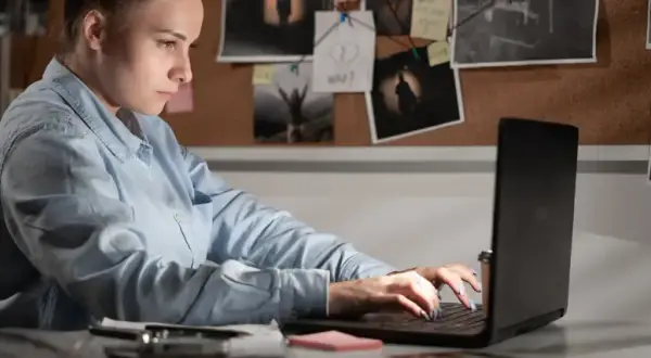 Giovane donna analizza prove su un laptop, un'indagine di criminologia a Milano.