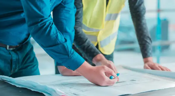 Un geometra di cantiere esamina un progetto con un collega.