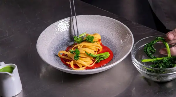 Impiattamento di pasta con broccoli e salsa rossa. La cura nei dettagli mostra come si diventa chef.