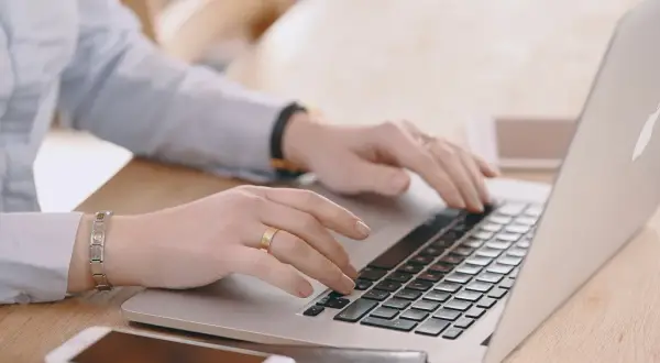 Mani che digitano su un laptop, cercando "università mercatorum recensioni" per valutare la formazione.