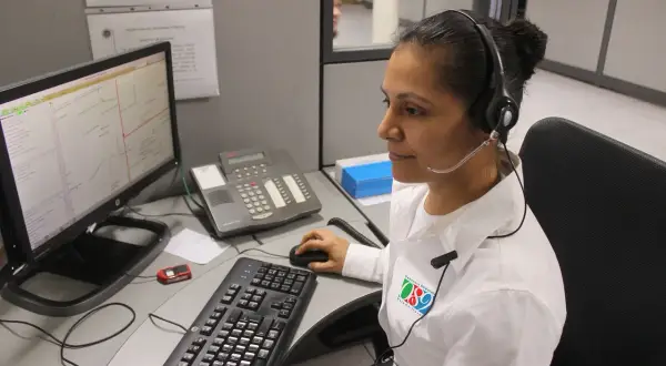 Operatrice al centro di controllo, forse per offerte lavoro cup strutture sanitarie, con cuffie e microfono, davanti a un computer con mappa.
