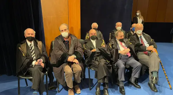 Uomini in toga seduti, alcuni con mascherina. Un uomo anziano potrebbe diventare avvocato a 50 anni, dimostrando che non è mai troppo tardi.