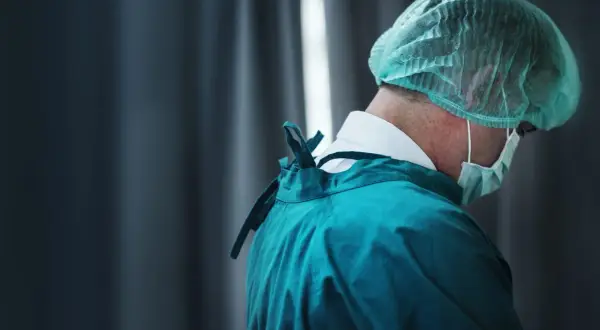 Professionista sanitario in camice verde e cuffia, con mascherina. Cerca offerte lavoro OSS per un futuro nel settore.