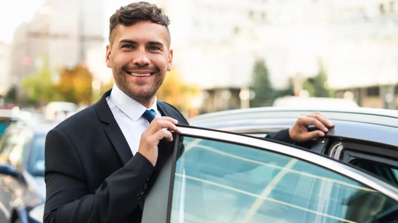 Un sorridente agente di commercio in giacca e cravatta apre la portiera di un'auto, pronto per un nuovo appuntamento.