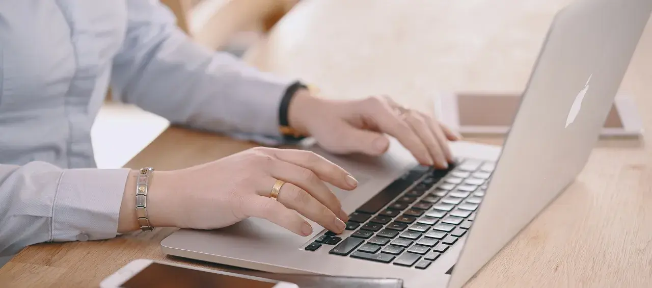 Mani che digitano su un laptop, cercando "università mercatorum recensioni" per valutare la formazione.