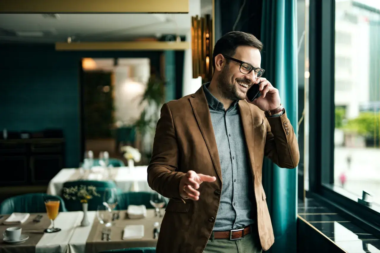 Un uomo sorride al telefono, un esempio di come un **innovation manager cosa fa**: gestisce idee e progetti con entusiasmo, in un ambiente moderno.