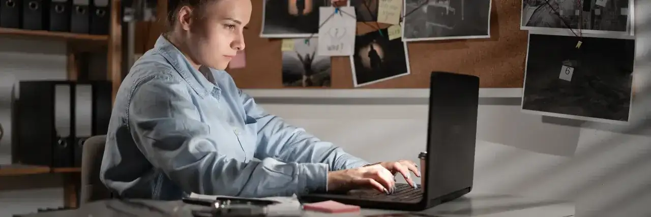Giovane donna analizza prove su un laptop, un'indagine di criminologia a Milano.