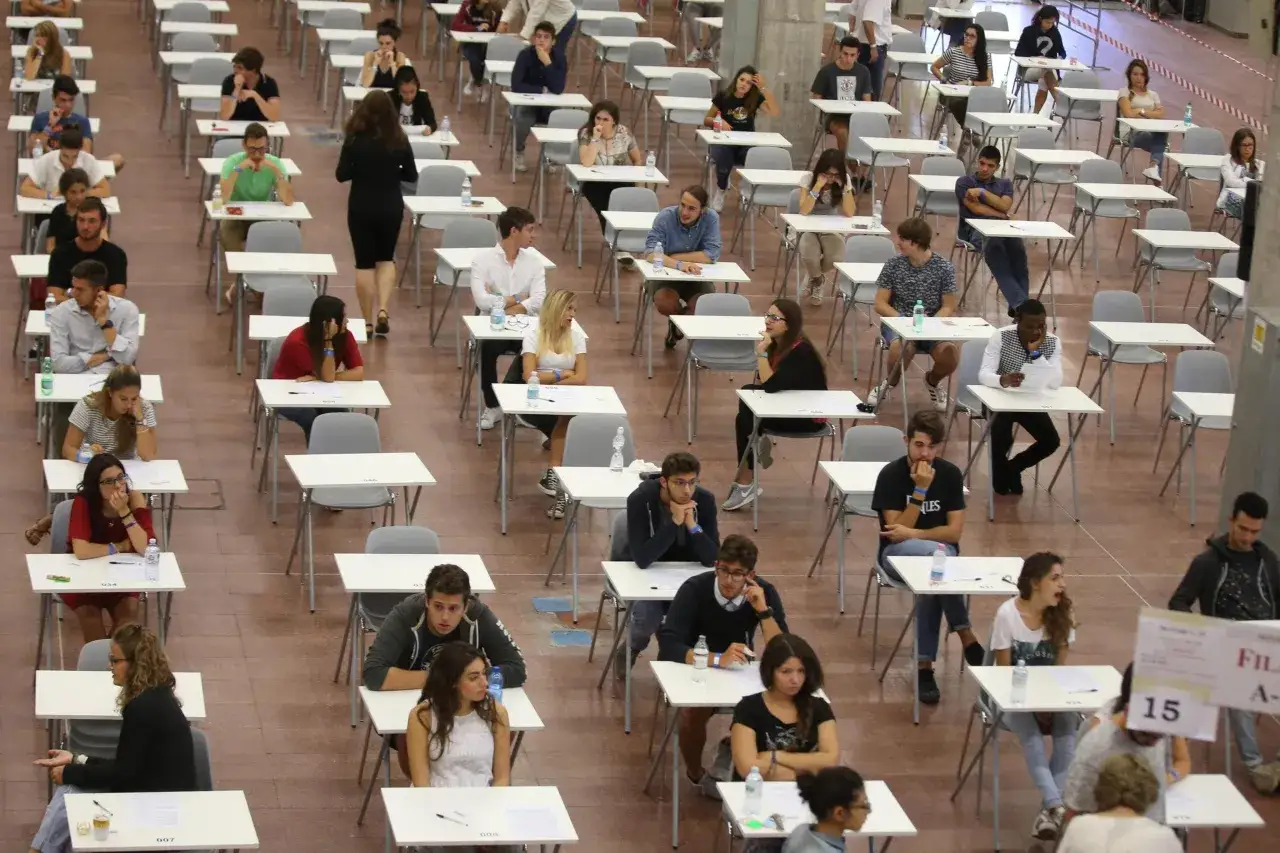 Studenti concentrati in un'aula d'esame, affrontando una prova che sembra tra le università più difficili.