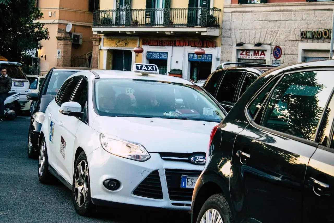 Un taxi bianco in fila con altre auto in una strada cittadina. Chiss&agrave; quanto guadagna un tassista con questo traffico.