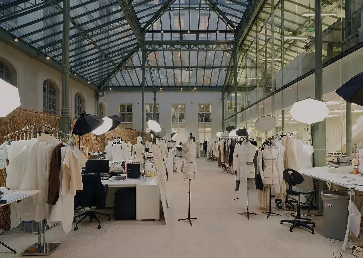 Laboratorio di moda con manichini, abiti appesi e luci, dove un visual designer d&agrave; vita alle sue idee.