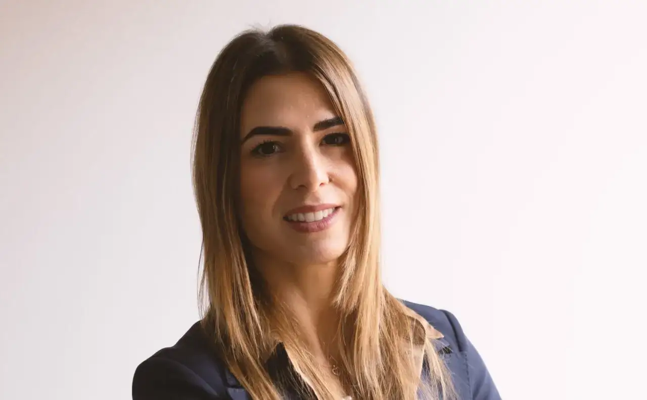 Donna sorridente in giacca blu, con capelli lunghi e castani. Potrebbe essere una professionista alla ricerca di offerte lavoro avvocato.