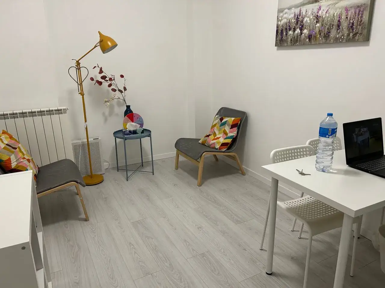 Studio di psicoterapia accogliente con sedie, tavolino, lampada e quadro. Qui si discute quanto guadagna uno psicoterapeuta.