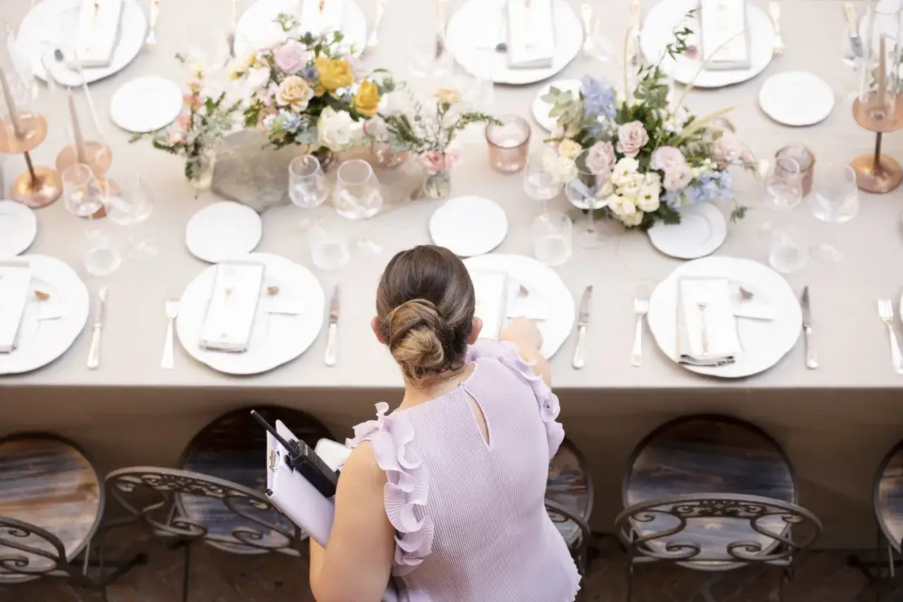 La wedding planner cosa fa? Organizza ogni dettaglio, dalla tavola imbandita con fiori pastello ai dettagli per gli ospiti, coordinando tutto con un walkie-talkie.