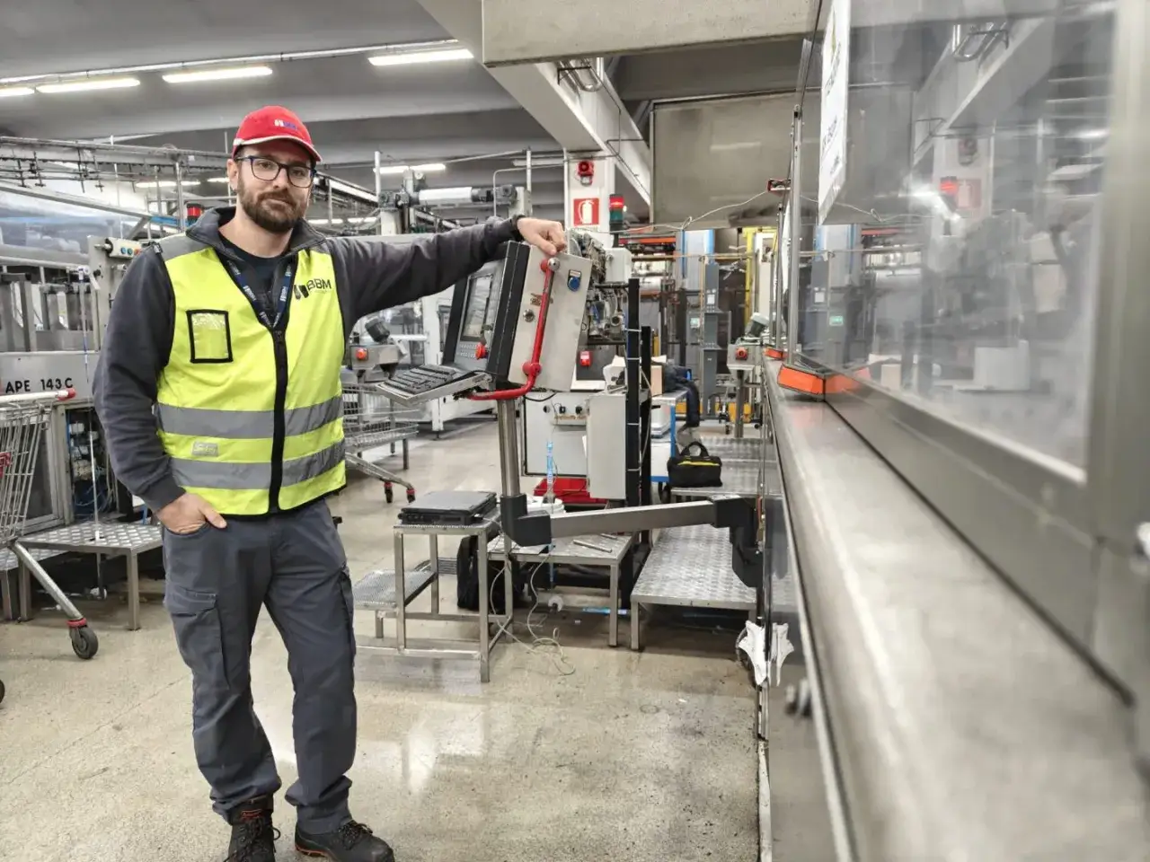 Operaio con giubbotto alta visibilità e cappellino rosso in un impianto industriale. Cerco lavoro trasfertista, pronto per nuove sfide.