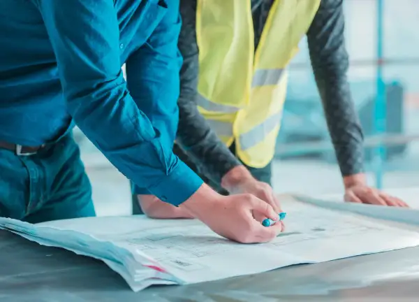 Un geometra di cantiere esamina un progetto con un collega.